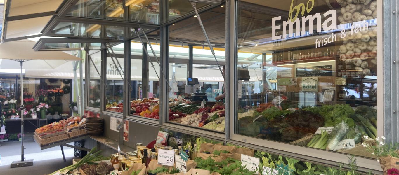 Frisches Gemüse ausgelegt vor dem Bio Stand am Stadtmarkt. Kräuter und verschiedenes frisches Obst. 